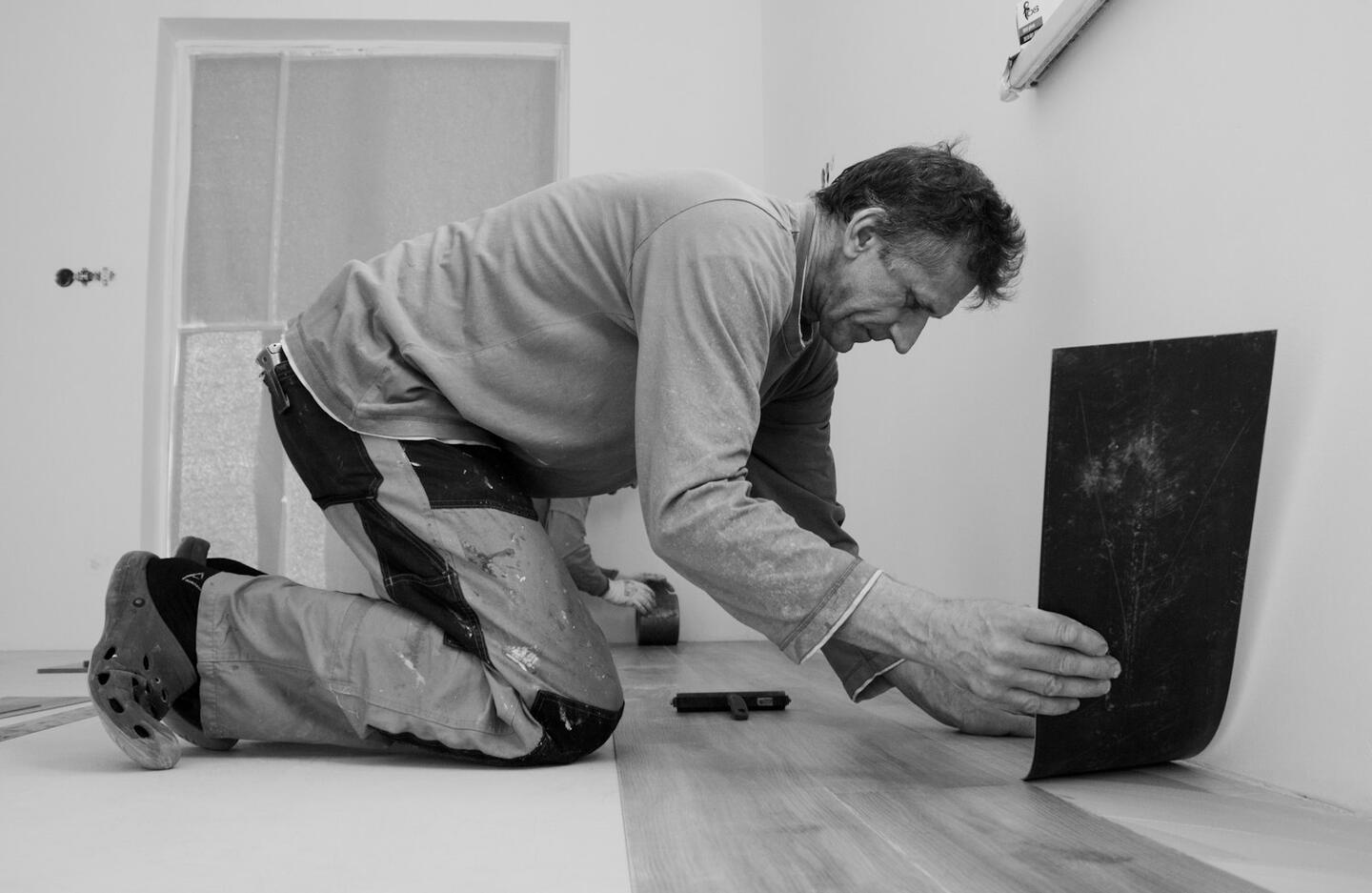 A fitter kneeling to set out a floor