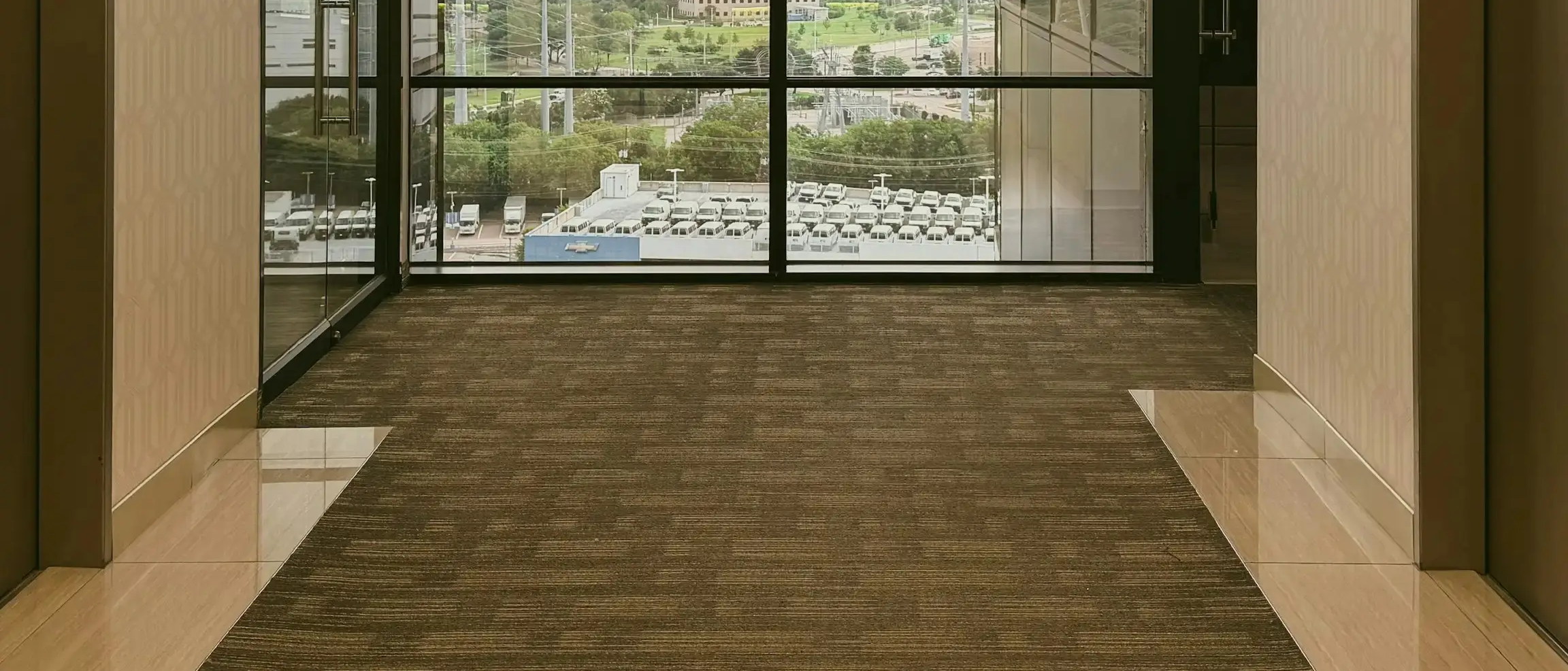 Patterned commercial carpet tile across an office corridor and lift lobby